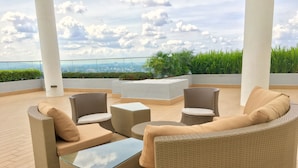 A rooftop terrace with wicker furniture, a glass-top table, and a view of the cityscape. - Pinnacle Tower Johor Bahru (Johor Bahru)