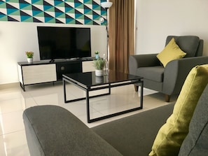 A modern living room with a sofa, a coffee table, a TV, and a side table with a plant.