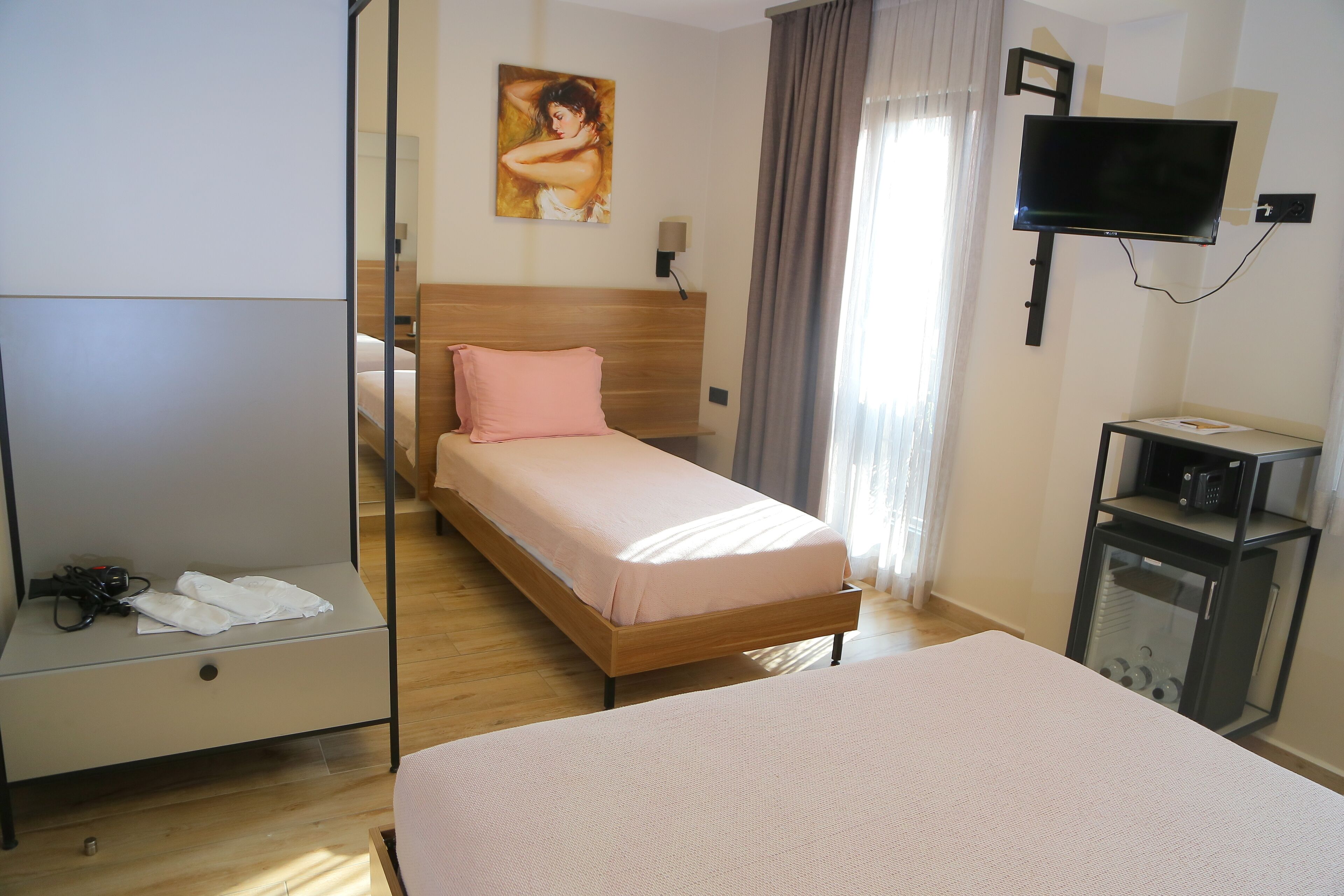 A hotel room with a bed, a bedside table, a TV, and a small cabinet.