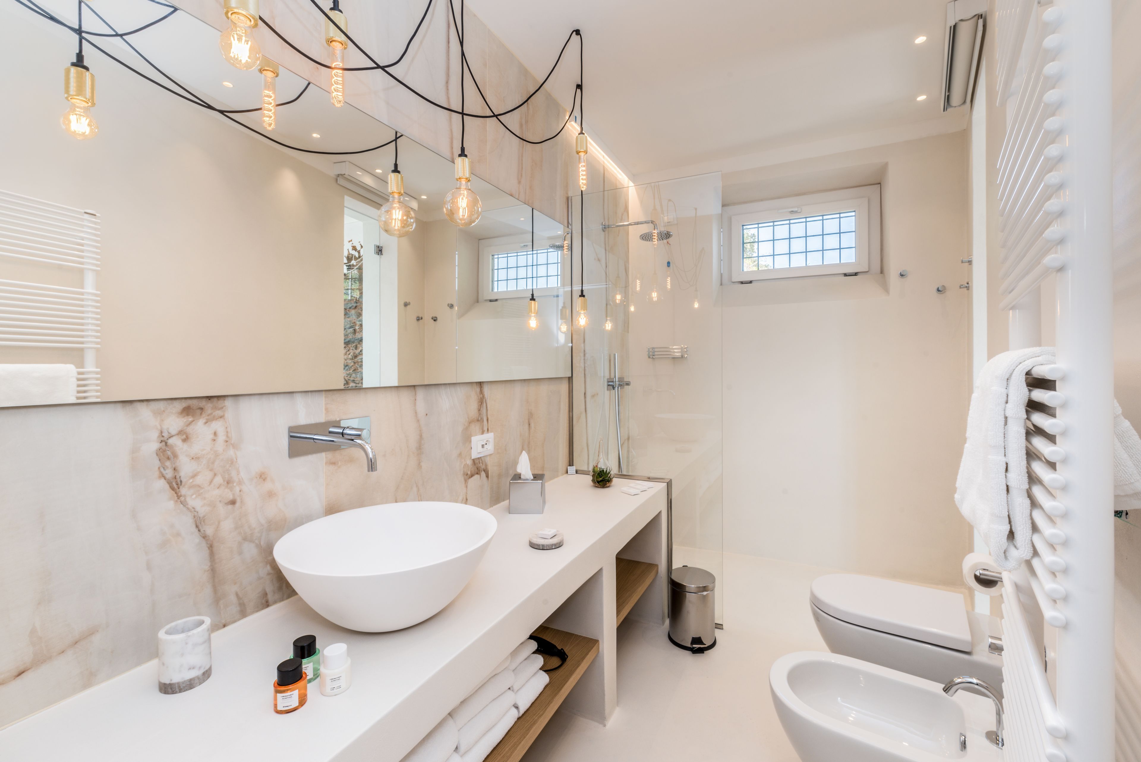 Une salle de bain moderne avec un grand lavabo blanc, un miroir et un espace douche.
