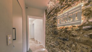A hallway with a stone wall and a sign that reads "THE FIRST".