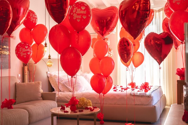 A room with a bed, a sofa, and a table with red heart-shaped balloons and rose petals. - Il Sogno di Manarola by The First (Riomaggiore)