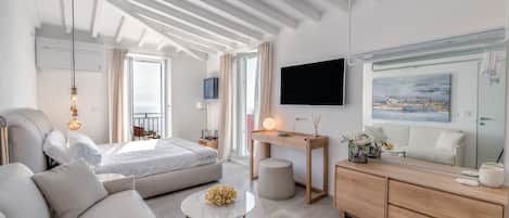 Un salon moderne et bien éclairé, comprenant un canapé, une table basse ronde, un lit, un bureau et un téléviseur.