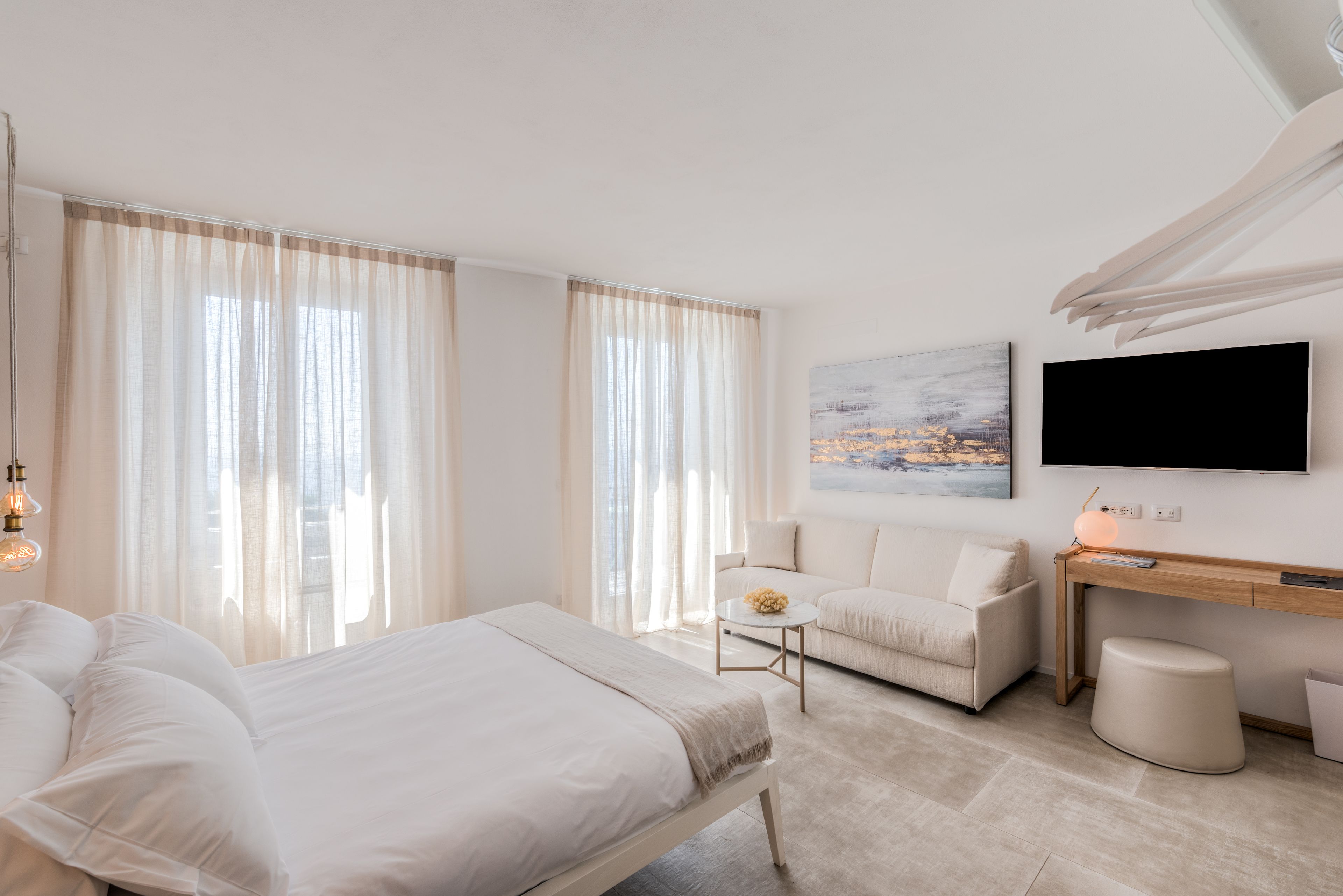 Une chambre d’hôtel moderne équipée d’un lit, d’un canapé, d’un bureau et d’une télévision.