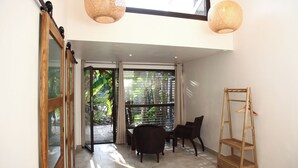 A modern interior with a sliding glass door leading to a balcony, a wooden chair, a small table, and a wooden shelf. - Villa Margaux (Fargues-Saint-Hilaire)
