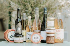 A selection of food and drink items, including bottles of wine and jars of preserves, displayed on a table. - Hôtel du Chateau (Tour-en-Sologne)