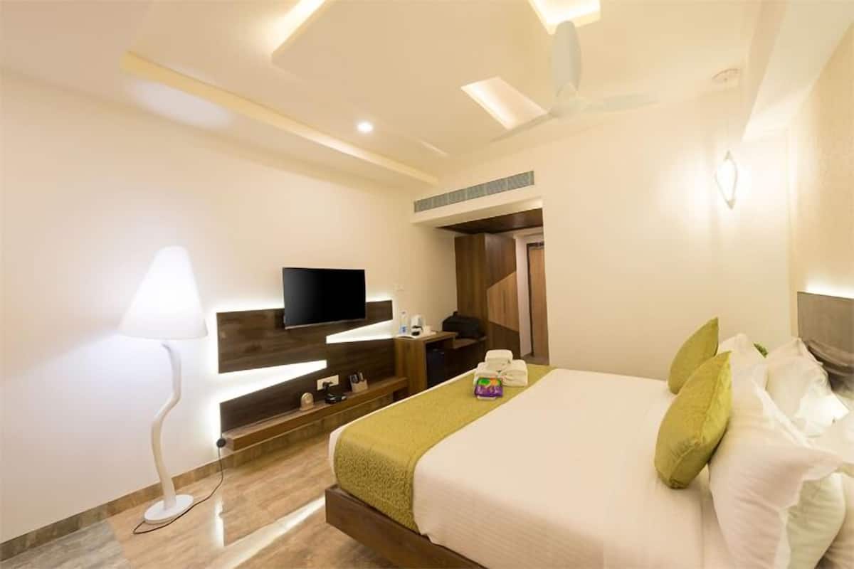 A hotel room with a bed, a TV, a desk, and a lamp.