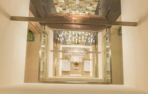Un interior moderno con una lámpara central, paredes espejadas y techo de madera.