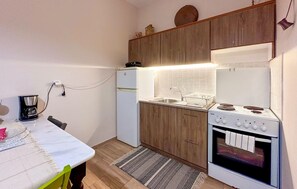 Une cuisine compacte équipée d’un réfrigérateur, d’une cuisinière et d’un évier, de placards en bois et d’une machine à café.