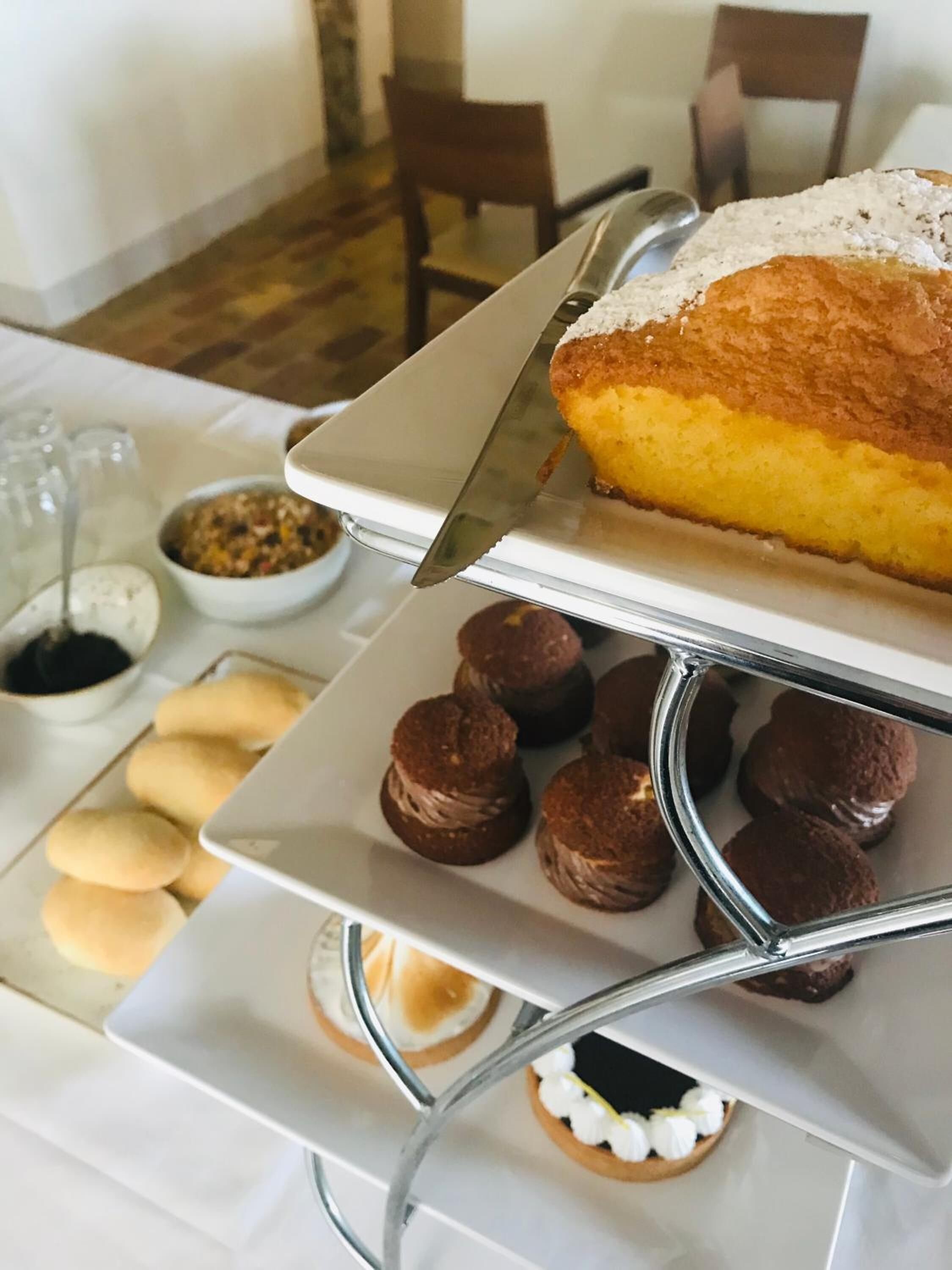 A dessert display with a cake, cupcakes, and cookies on a white table.