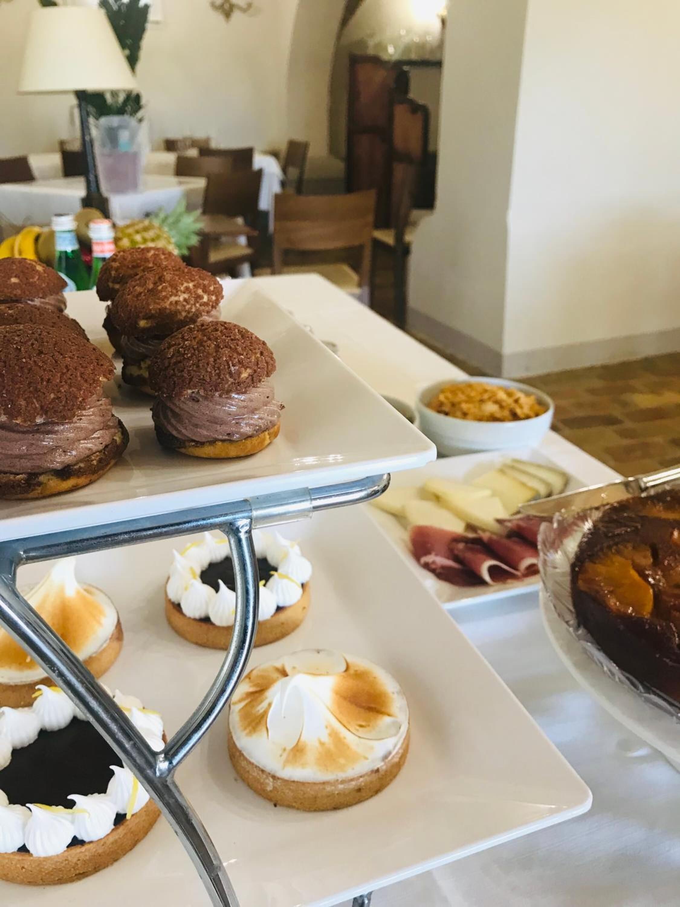 A dining table with various pastries and a plate of cheese and meats.