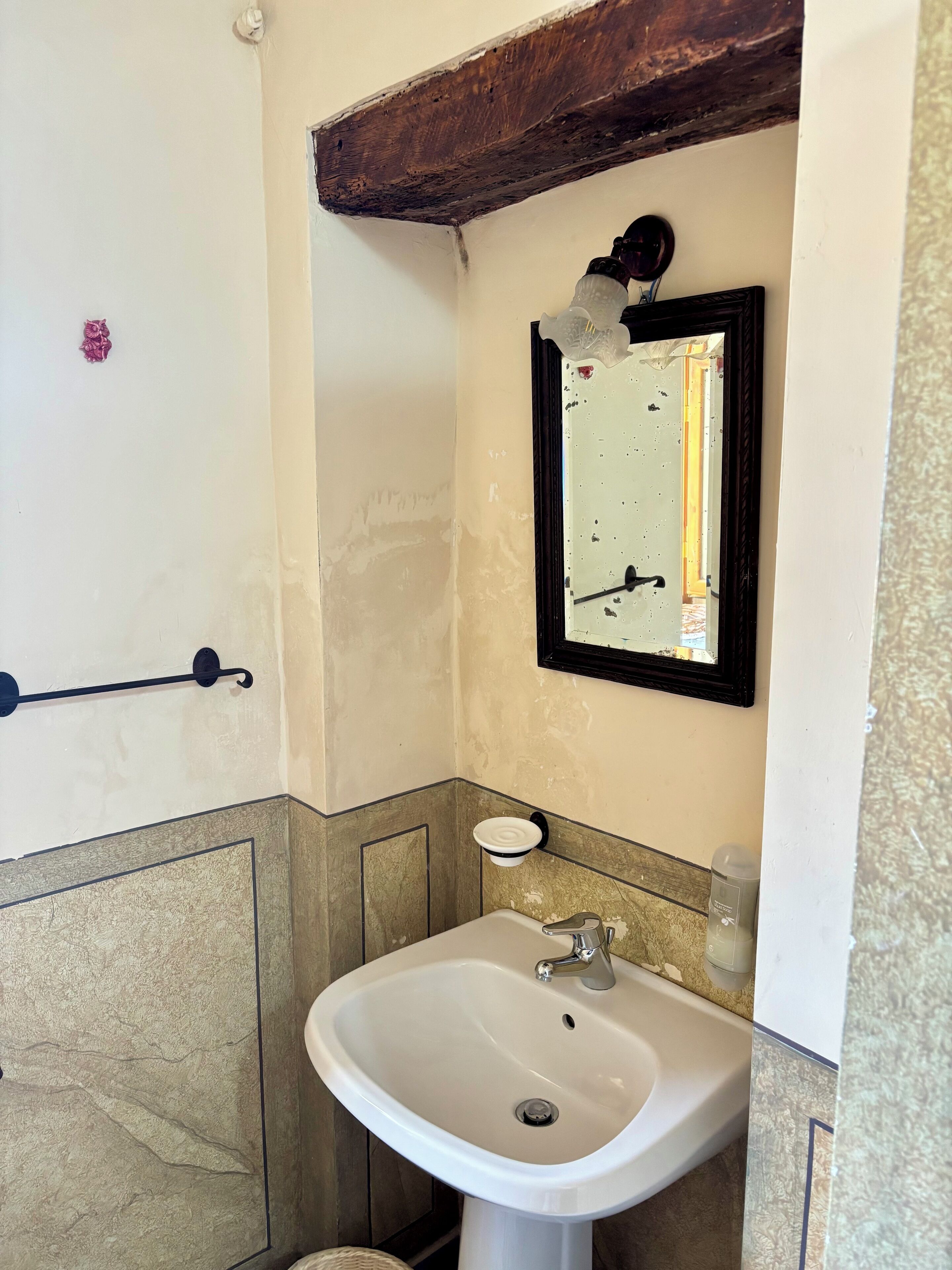 A bathroom with a white sink, a mirror, and a towel rack.