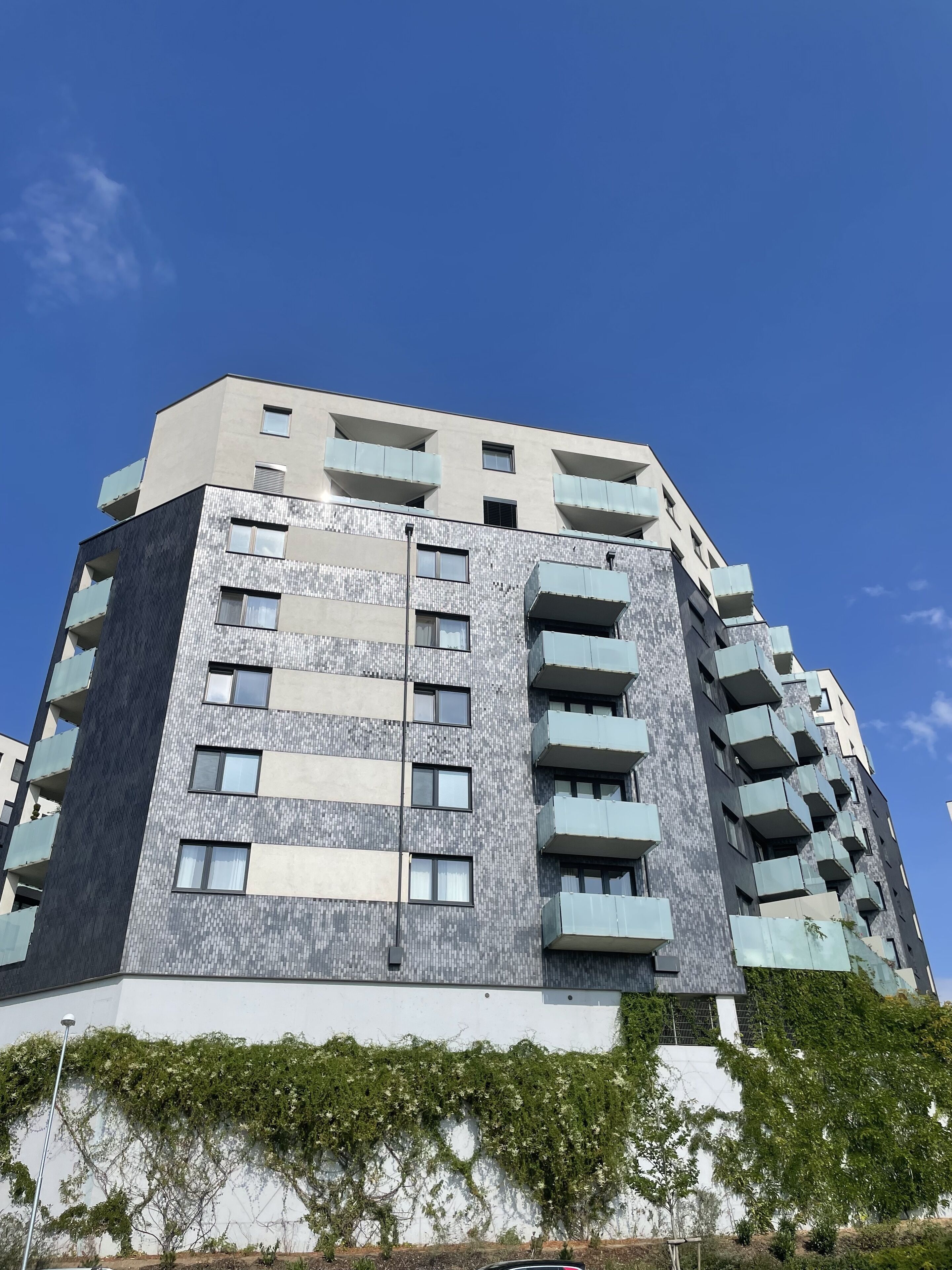 Un edificio a più piani con un design architettonico moderno, caratterizzato da balconi e una facciata decorata.