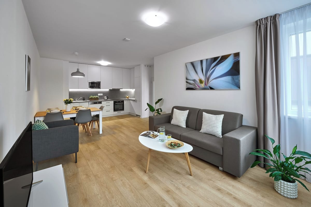 A modern living room with a grey sofa, a coffee table, and a dining area with a table and chairs.