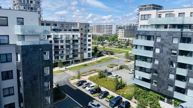 A modern apartment complex with multiple buildings, a parking area, and a green space with trees. - CityWest Apartments (Prague)