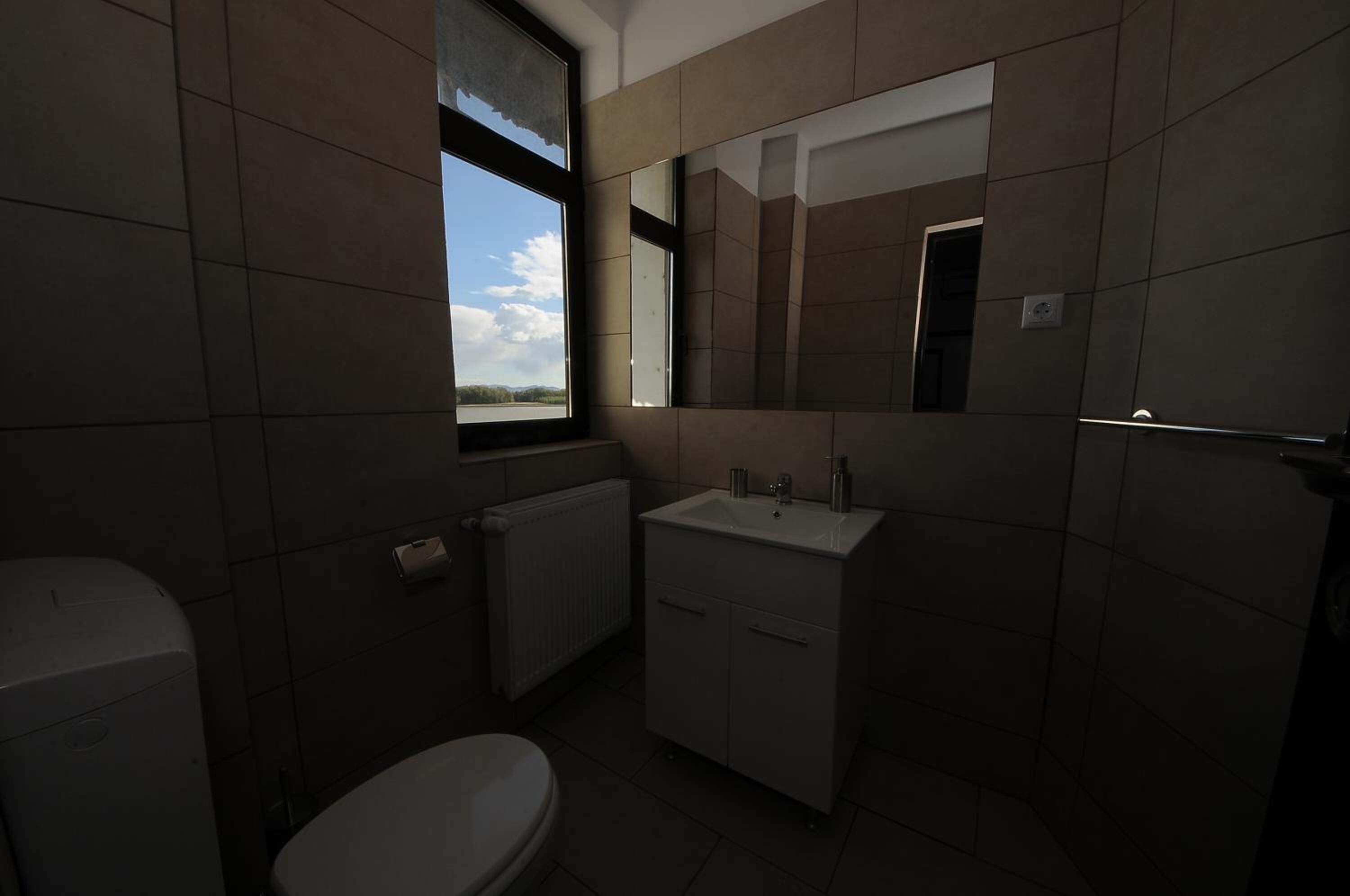 Un baño con inodoro, lavamanos y ventana.