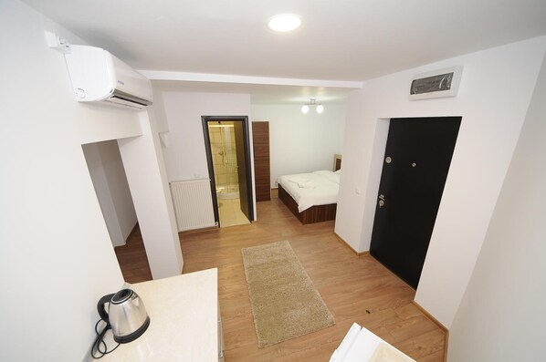 A hotel room with a bed, a black door, a white radiator, and a coffee maker.