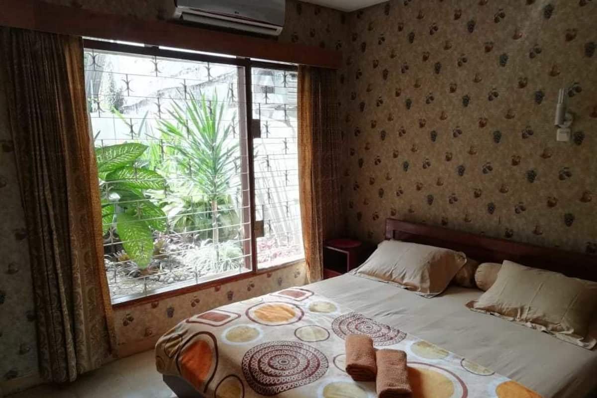 A bedroom with a bed, curtains, a window, and a wall with a pattern.