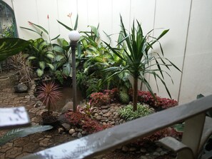 A small garden area with various plants, a decorative lamp post, and a stone pathway. - Gio Guesthouse Bogor (Bogor)