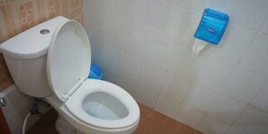 A white toilet with a blue tissue dispenser mounted on the wall. - Gio Guesthouse Bogor (Bogor)