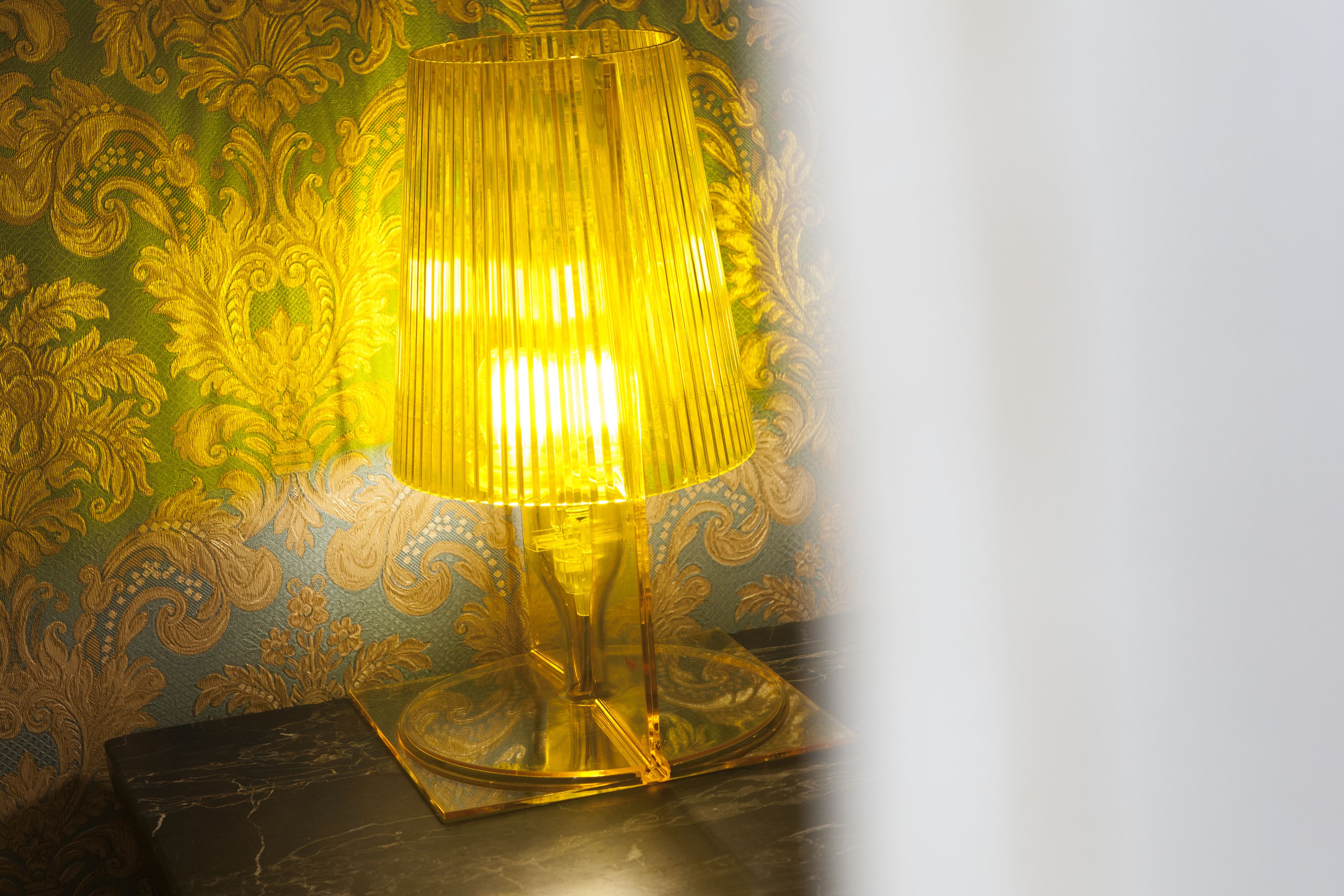 En bordslampa med en gul lampskärm, placerad på ett bord.