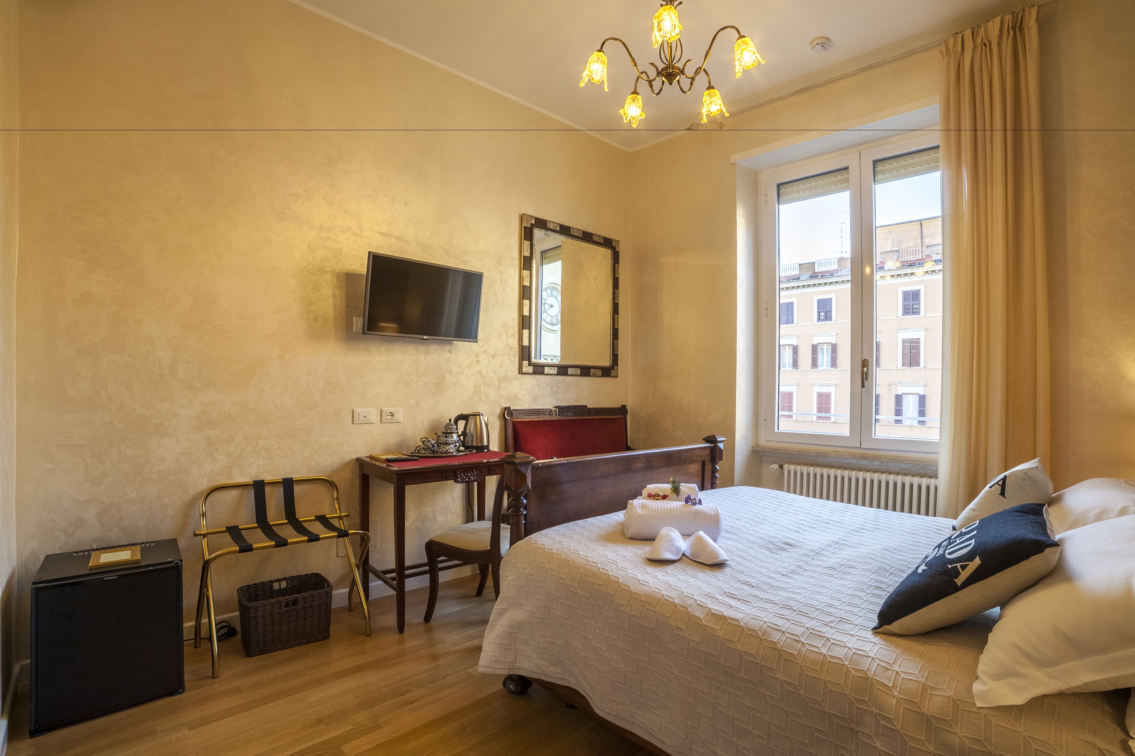 A hotel room with a bed, a desk, a chair, a television, and a window with curtains.
