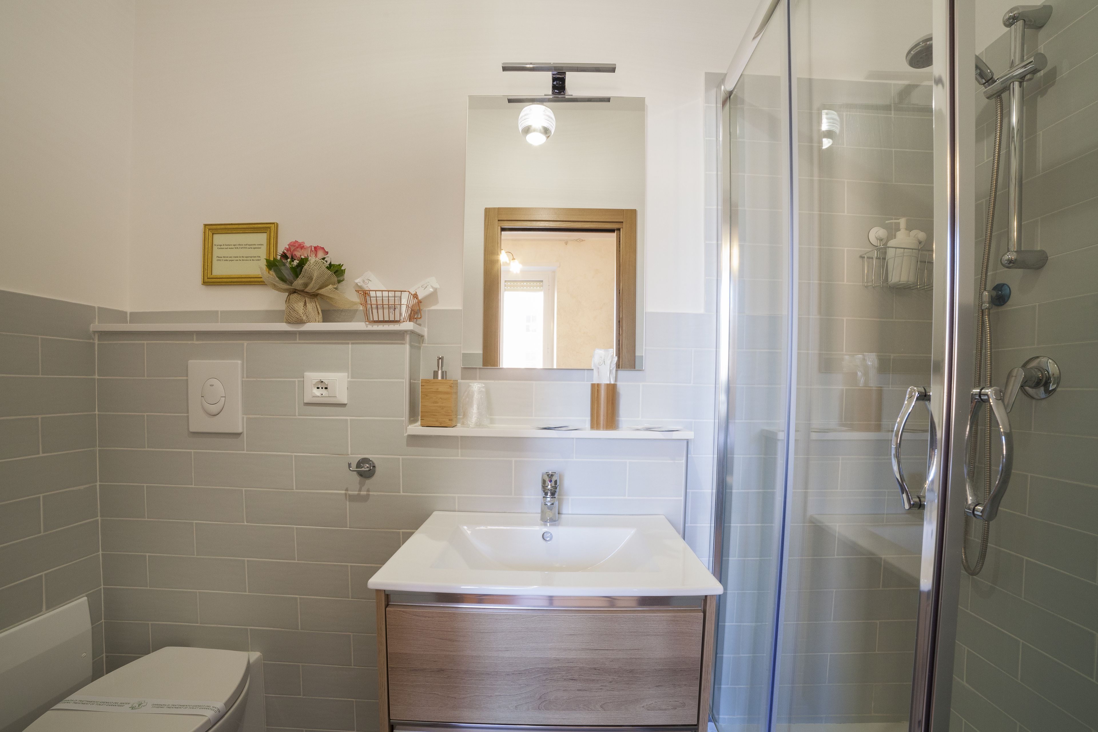 A modern bathroom with a glass shower enclosure, a white sink, and a wooden vanity.