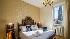 Una cama bien hecha con una computadora portátil, una lámpara y un cabecero decorativo.