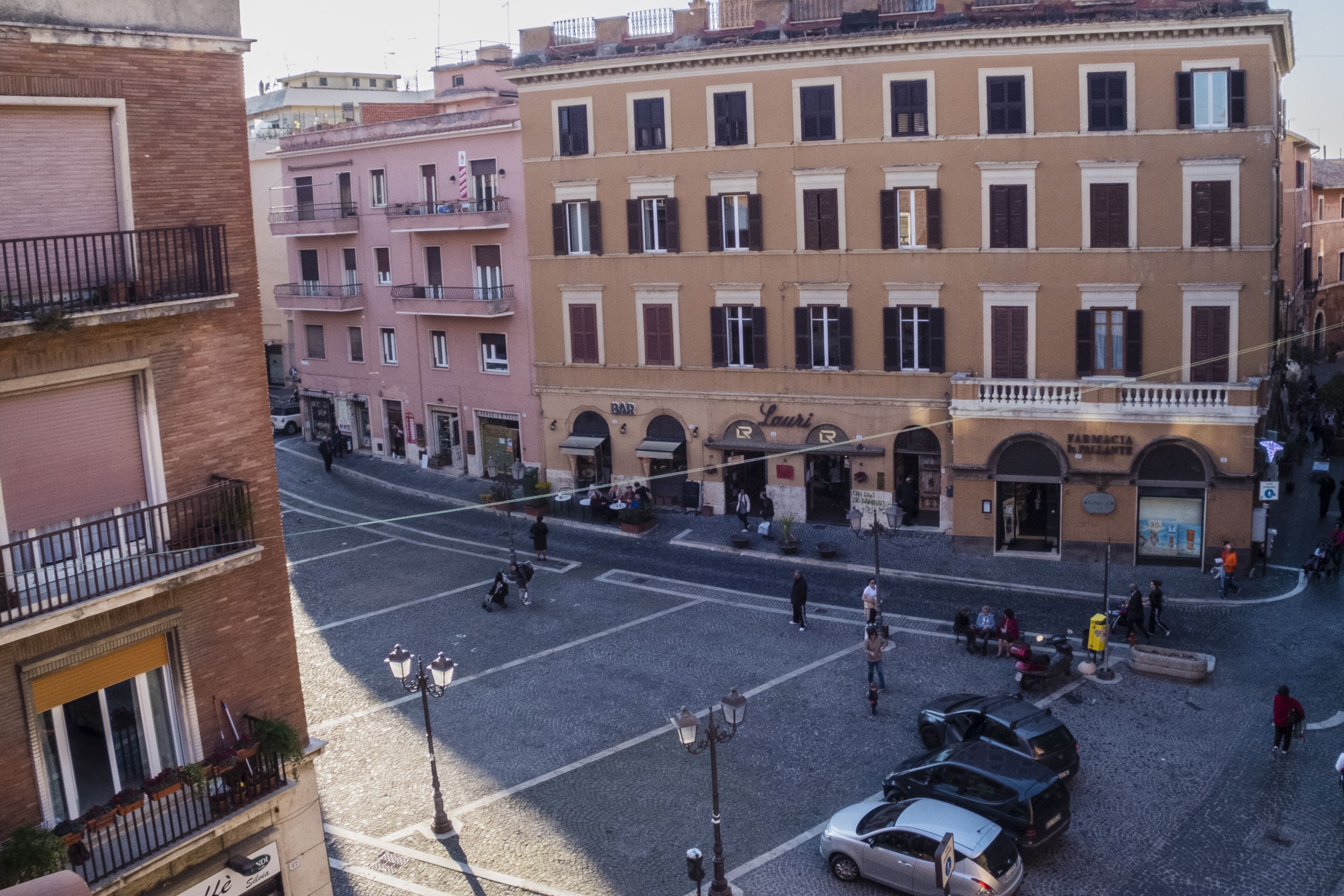 A street view with buildings, a crosswalk, and parked cars.