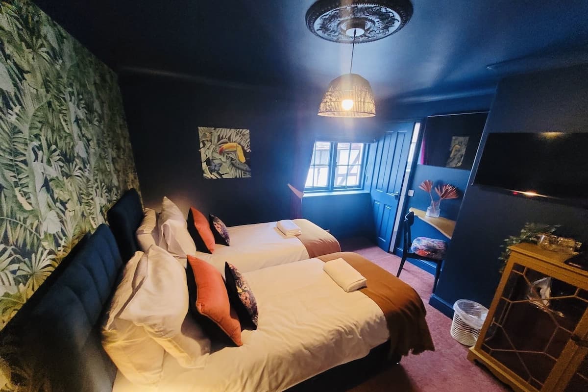 A hotel room with two beds, a large window, a television, and a decorative cabinet.