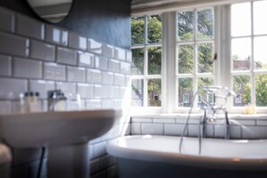 A kitchen with a large window, white tiles, and a sink.