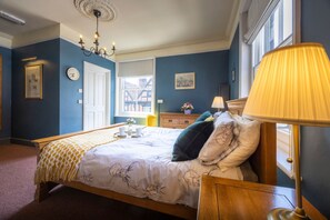 A bedroom with a bed, bedside table, lamp, and a window.
