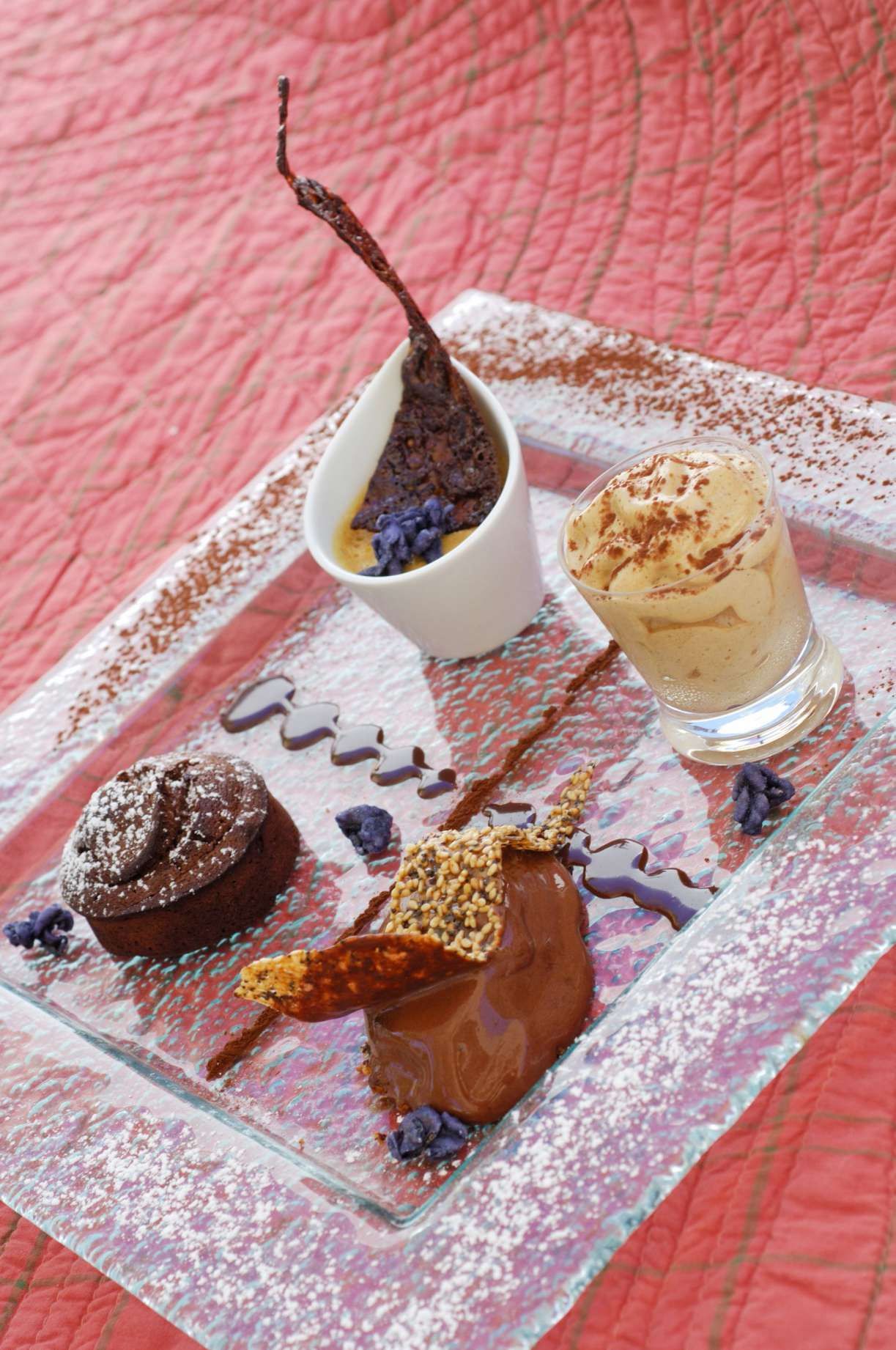Een presentatietafel met een chocoladedessert, een bolletje ijs en chocoladesaus op een oppervlak met structuur.