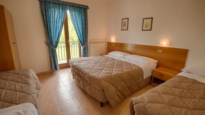 A hotel room with two beds, a wooden headboard, a window with curtains, and two wall-mounted lights. - Albergo della Corte (Pescasseroli)