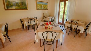 A dining area with two tables, chairs, and paintings on the walls. - Albergo della Corte (Pescasseroli)
