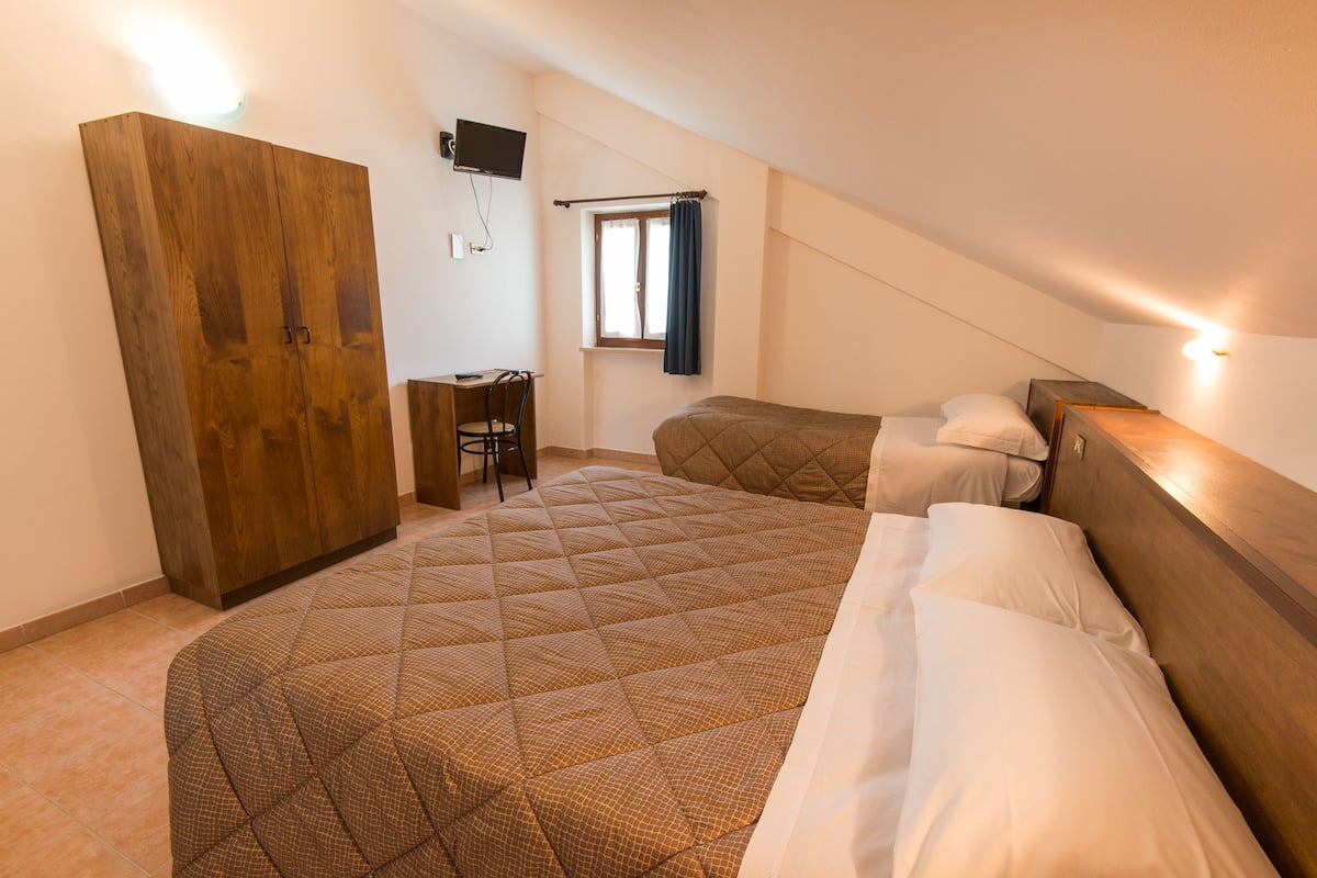 A bedroom with a large bed, a desk, and a wardrobe.