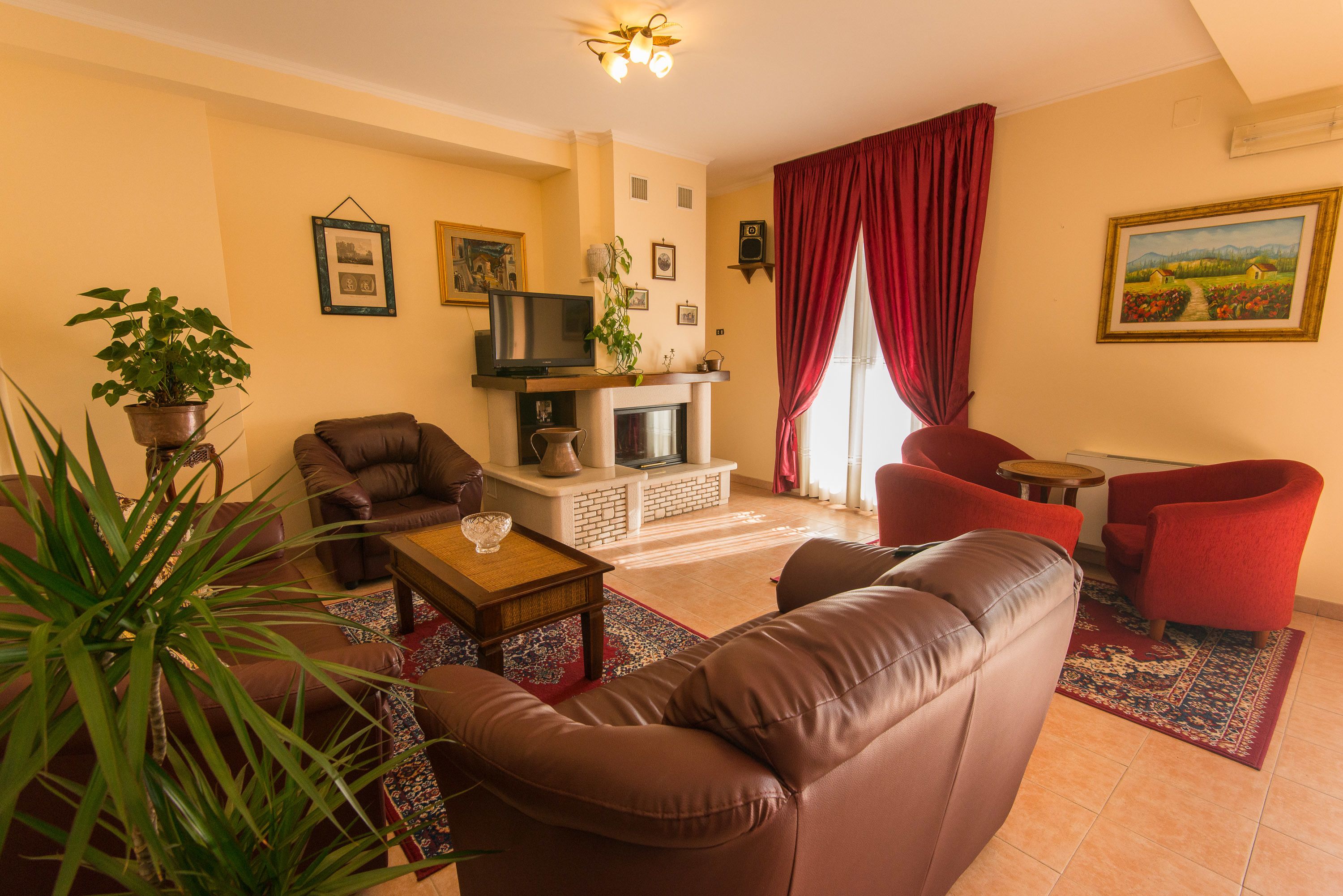 A living room with a fireplace, leather sofas, a coffee table, and a red chair.