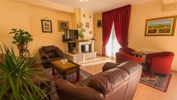 A living room with a fireplace, leather sofas, a coffee table, and a red chair.