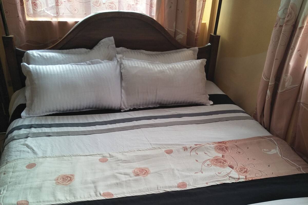 A bed with a floral bedspread, two pillows, and a headboard.