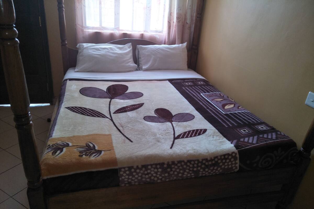 A bed with a floral-patterned bedspread, a wooden headboard, and white pillows.
