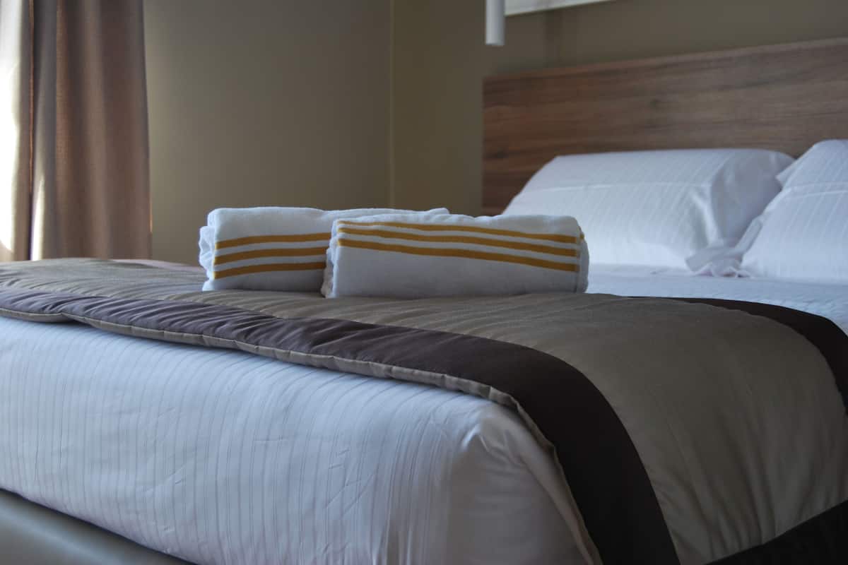 A neatly made bed with striped pillows and a dark headboard.