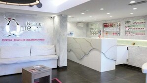 A modern reception area with a white sofa, a reception desk, and a wall-mounted TV. - 7th Floor Suite (Naples)