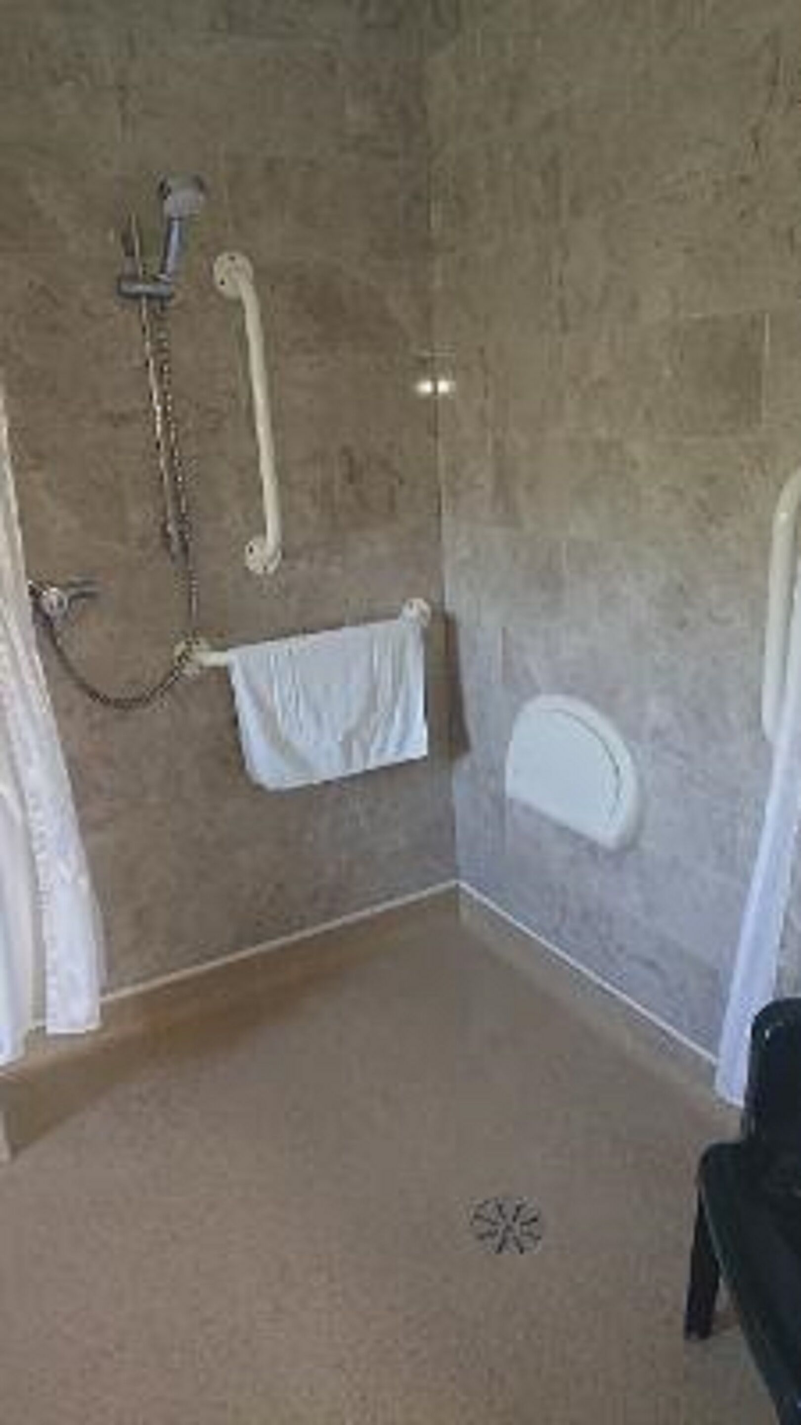 A bathroom with a shower, a towel rack, and a toilet.