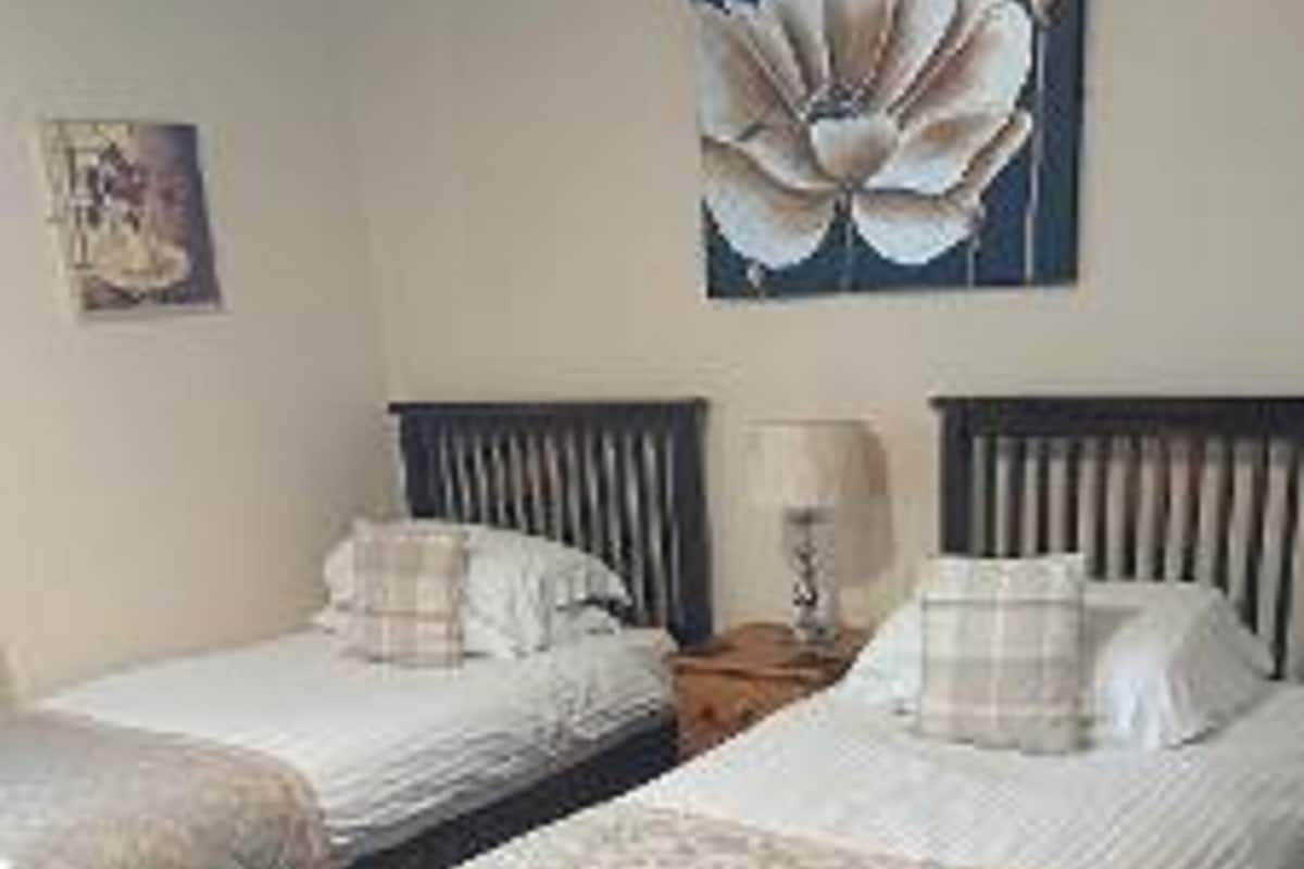 Two single beds with headboards, a nightstand, a lamp, and a large floral painting on the wall.
