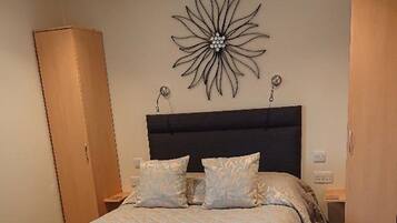 A bedroom with a large bed, a dark headboard, a decorative wall piece, and wooden wardrobes.