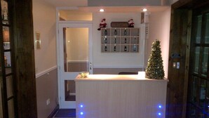 Un área de recepción con un árbol de Navidad, un mostrador de recepción y una pared con espacios numerados para correo.