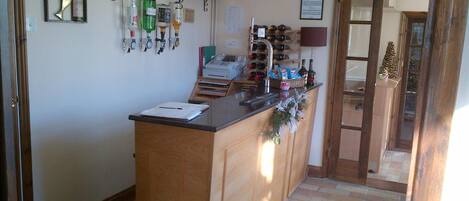 A bar area with a wooden counter, shelves with bottles, and a small Christmas tree.