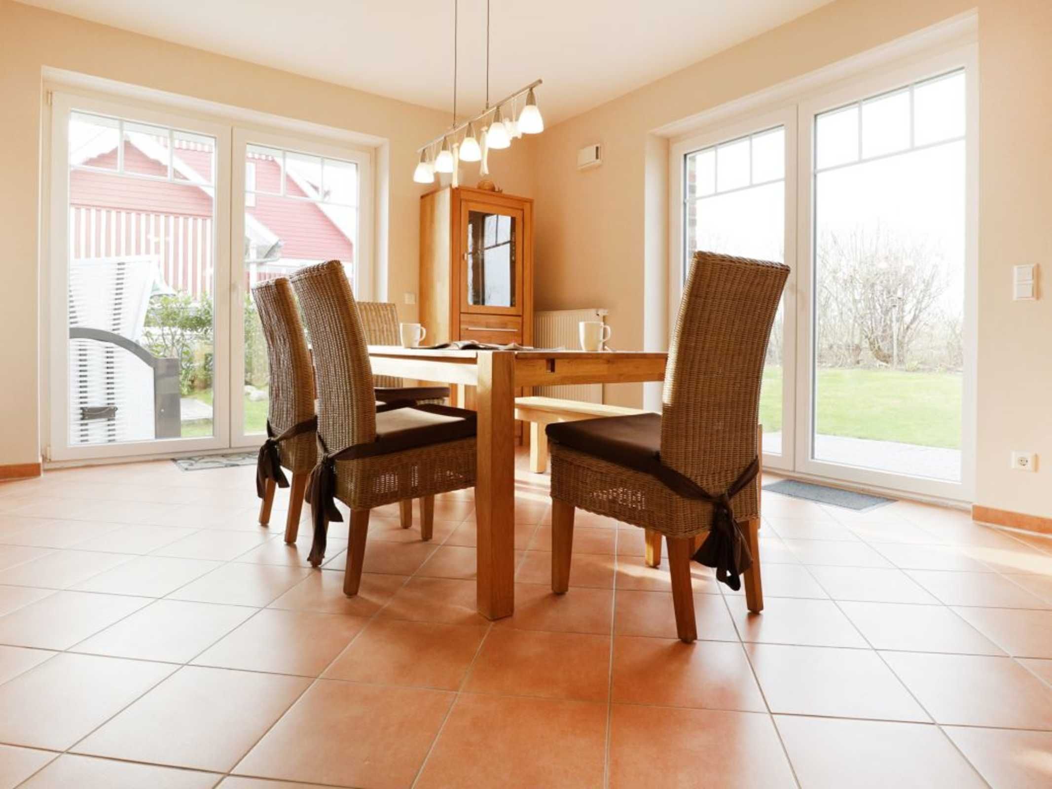 Een eetgedeelte met een tafel en vier stoelen, grote ramen en uitzicht op het omliggende landschap.
