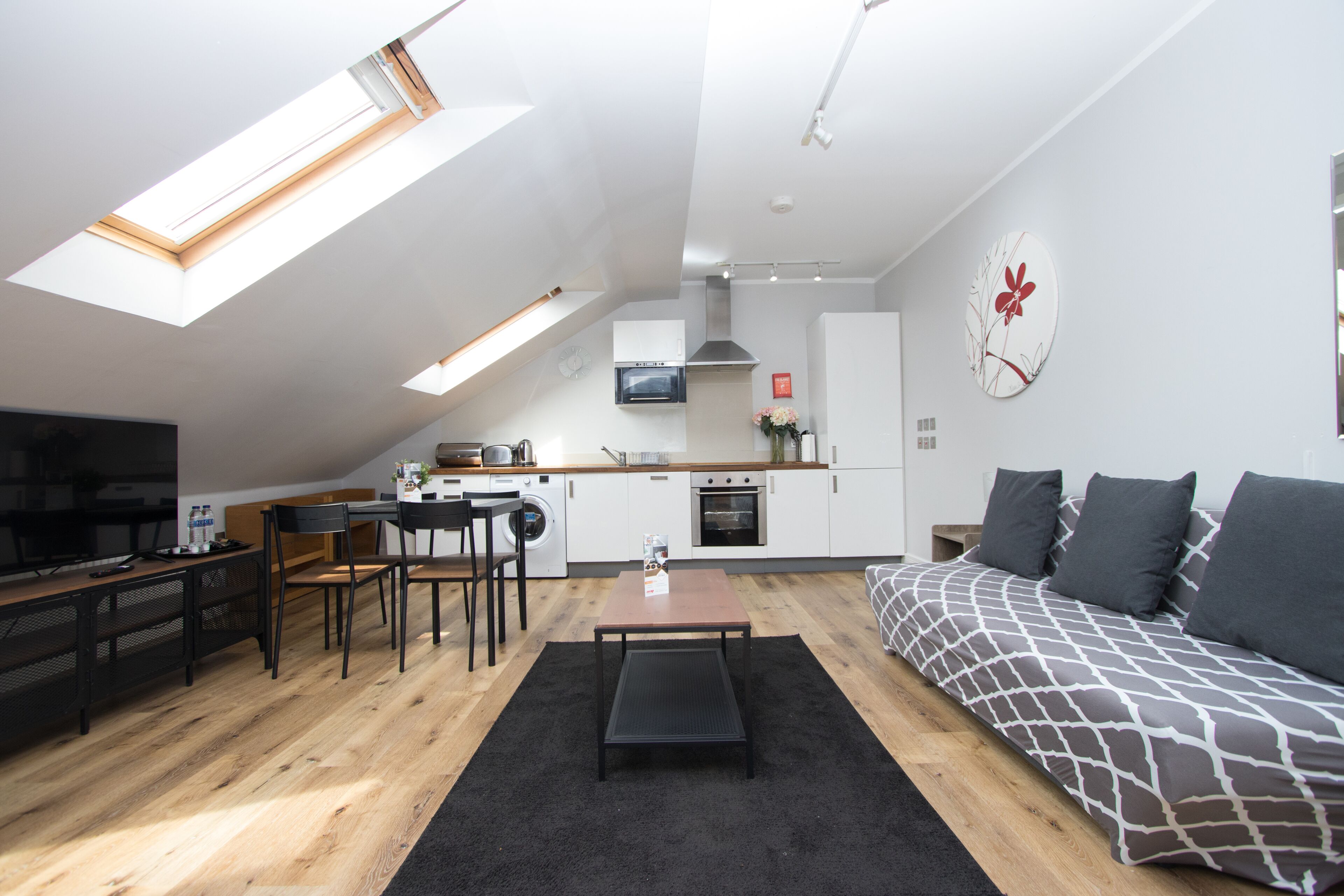 Un appartement moderne doté d’une cuisine de style industriel, d’un coin repas et d’un salon avec un canapé et un téléviseur.