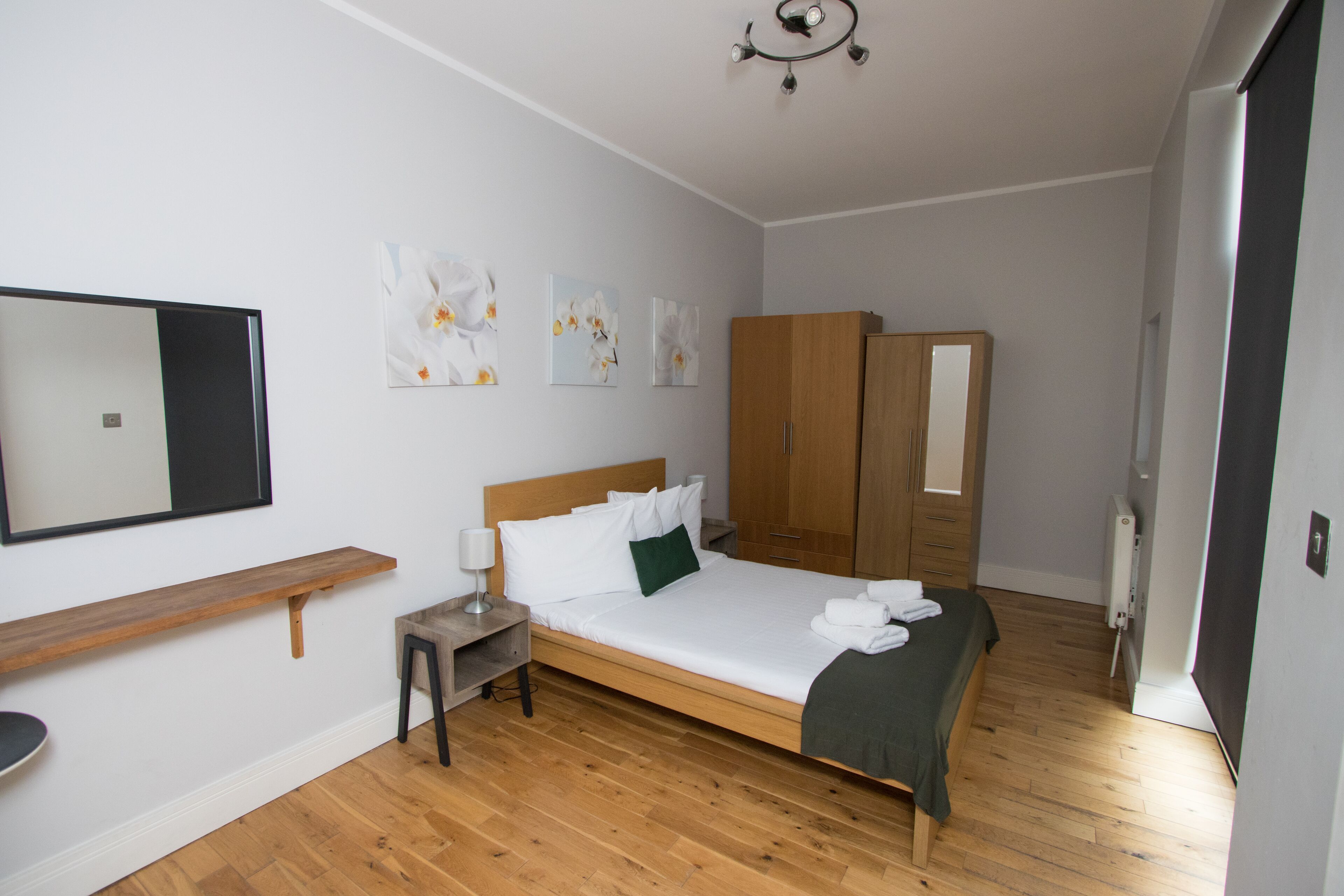 A bedroom with a wooden bed, a nightstand, a mirror, and a wardrobe.